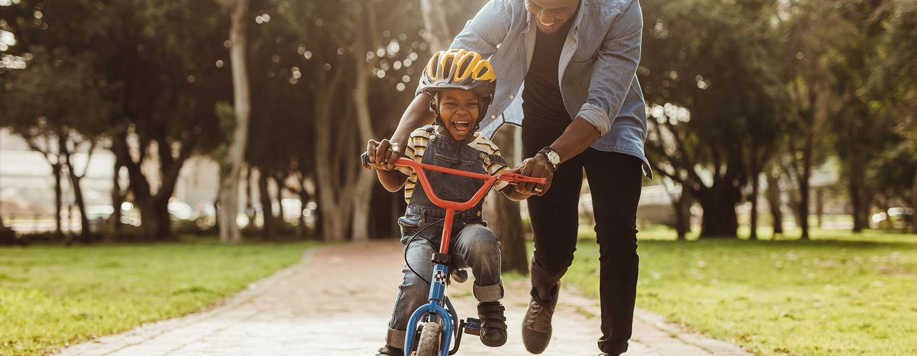 Father and child riding a bike in the park 